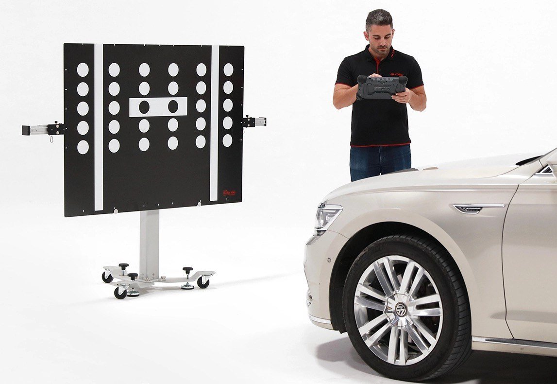 Técnico con panel de calibración ADAS y tableta de diagnóstico
